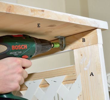 Patterinsuojus: Kiinnitä ylälevy (E). Patterinsuojus: Kiinnitä ylälevy (E).